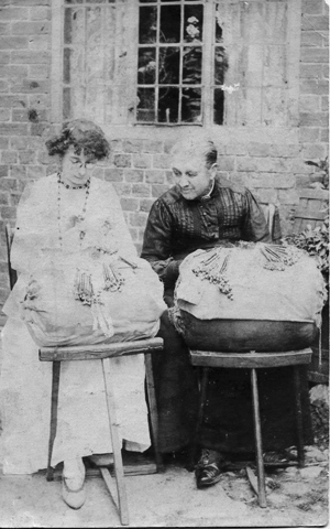 Two women sitting outside with lace pillows